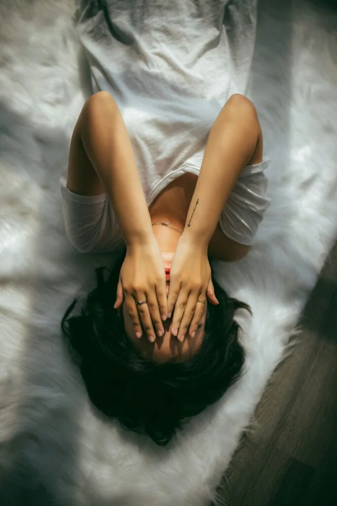 An overwhelmed young mother, lying on her bed, who needs time off, seeking for self care tips